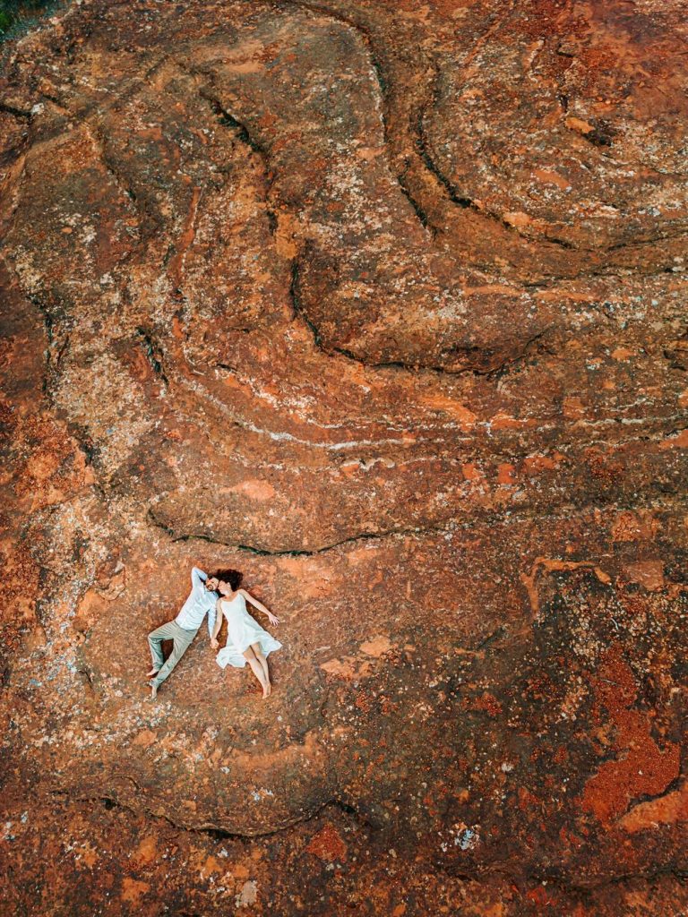 Aerial drone photograph of a couple lying on red rock