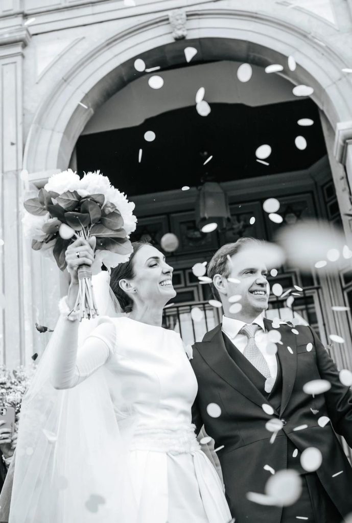 Black and white photograph of newlyweds leaving the church under confetti