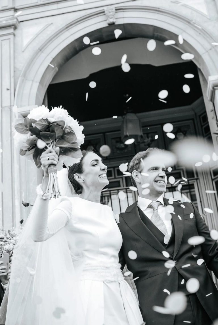 Black and white photograph of newlyweds leaving the church under confetti