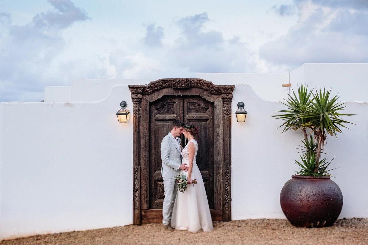 Bride and groom by a carved wooden door at a whitewashed villa in Cabo de Gata