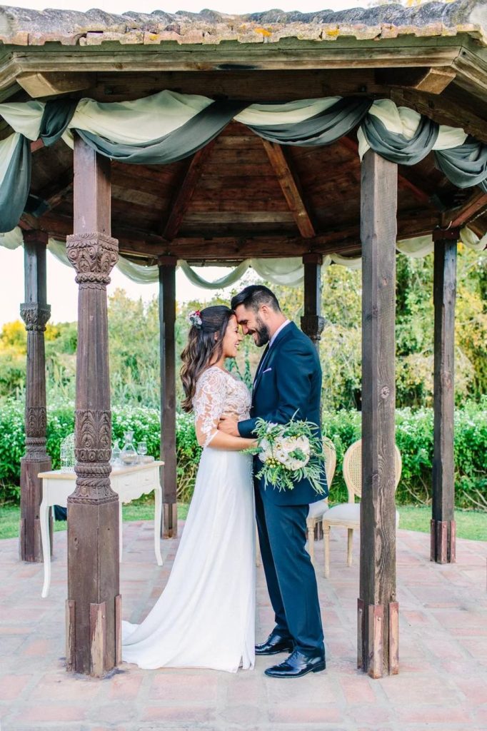 Bride and groom under a wooden pergola in a garden