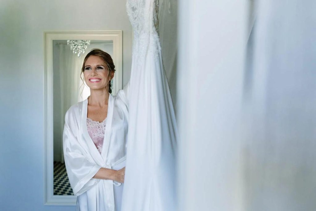 Bride getting ready, smiling softly by the window