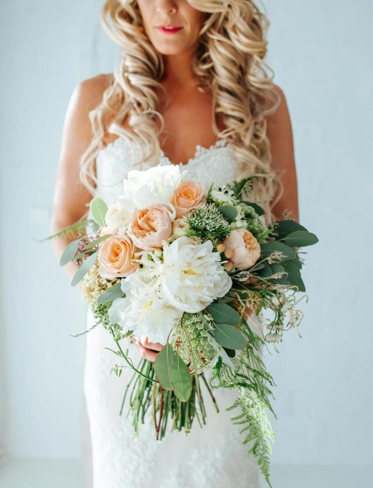 Bride holding a bouquet of peach roses and white peonies