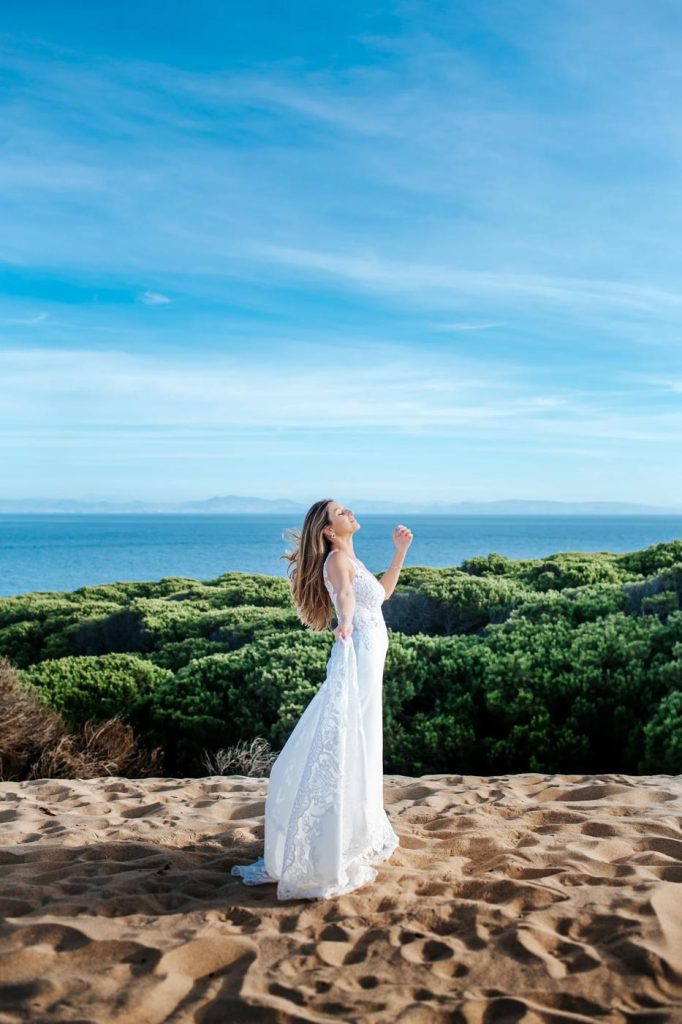 Bride standing among the dunes above the sea in Tarifa