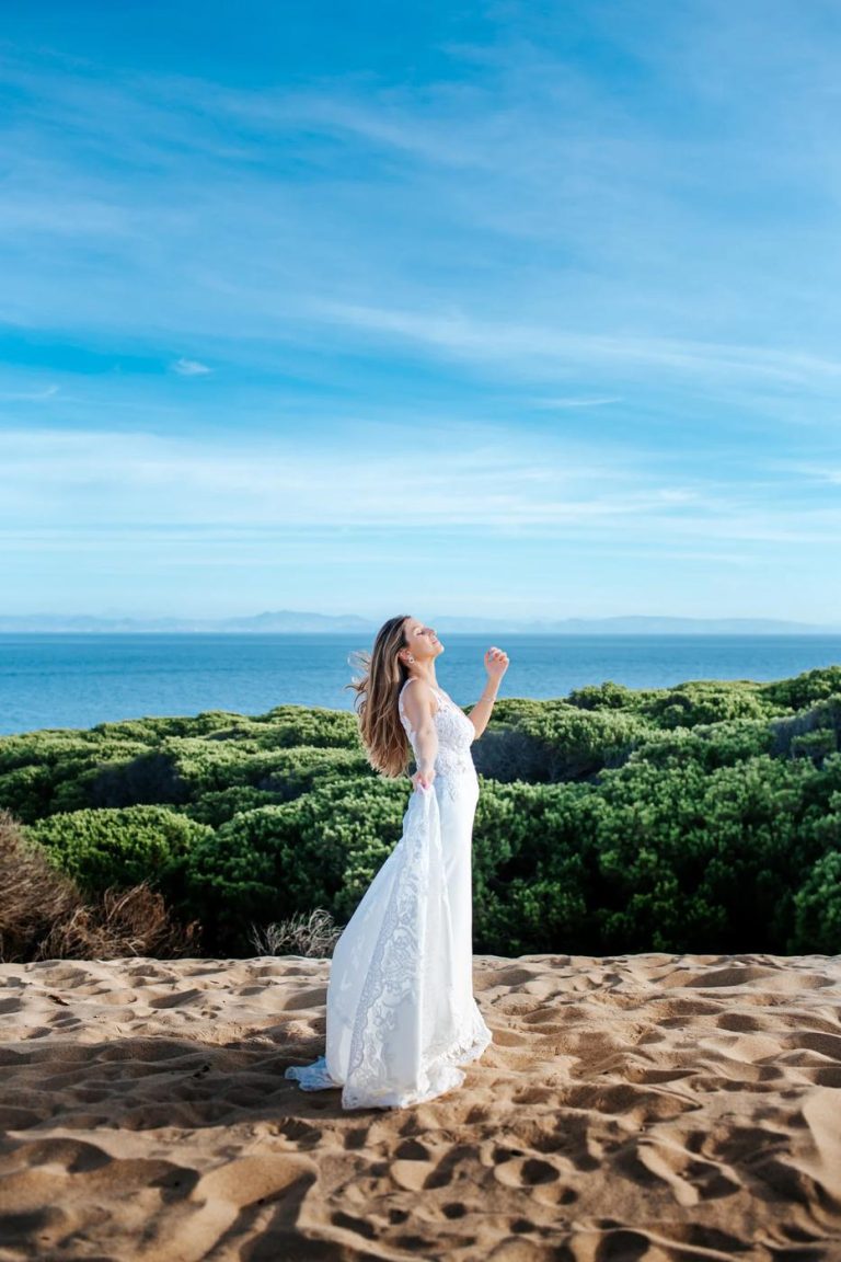 Bride standing among the dunes above the sea in Tarifa