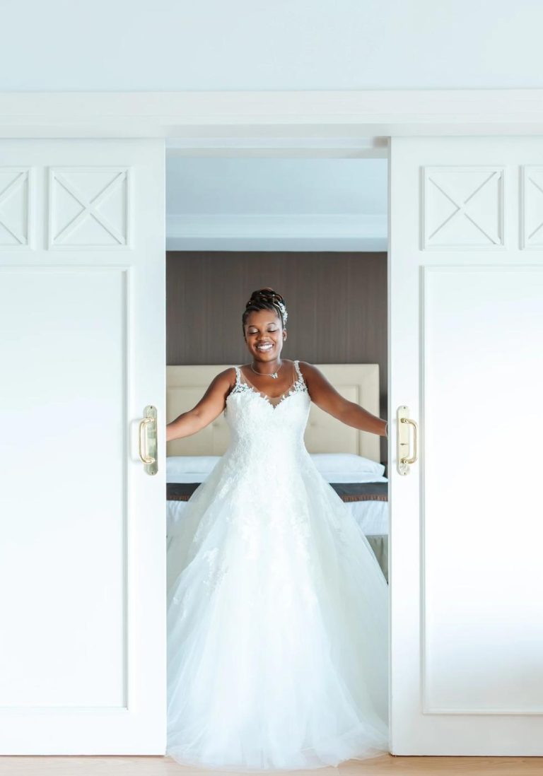 Bride standing in a bright white doorway on her wedding morning