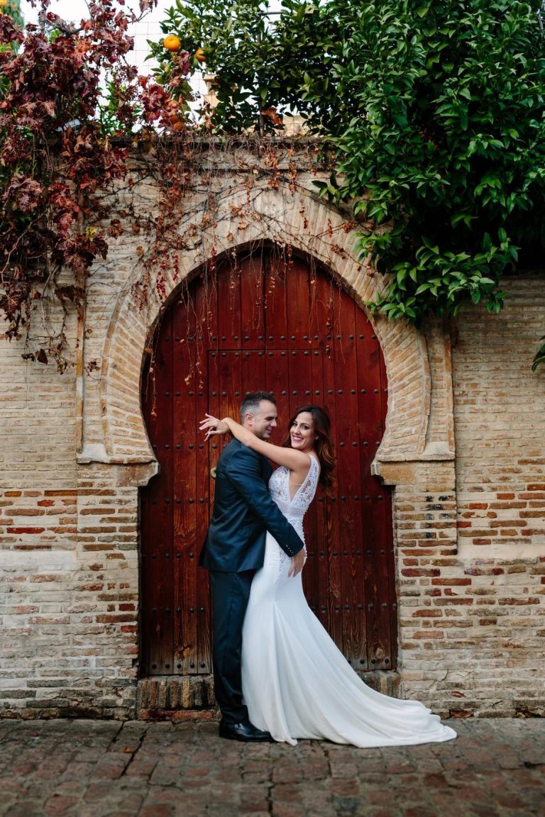 Couple embracing in front of a red Moorish door in Granada