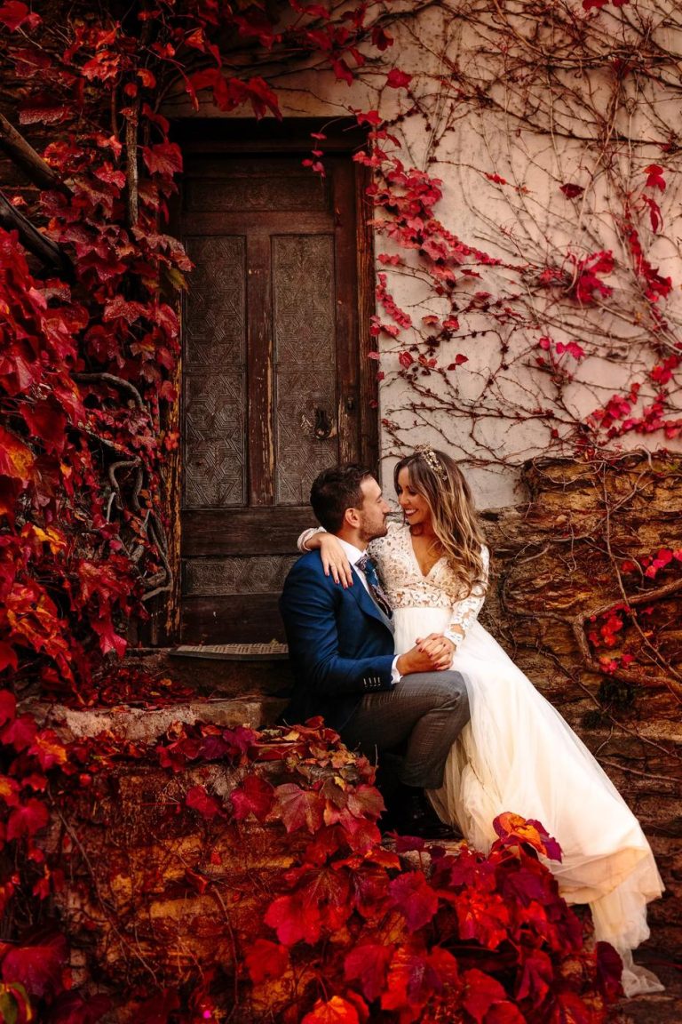 Couple seated among red autumn ivy by an old wooden door