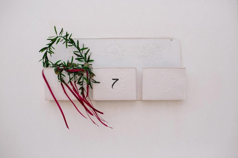 Wedding detail: wild greenery and red flowers beside table number seven